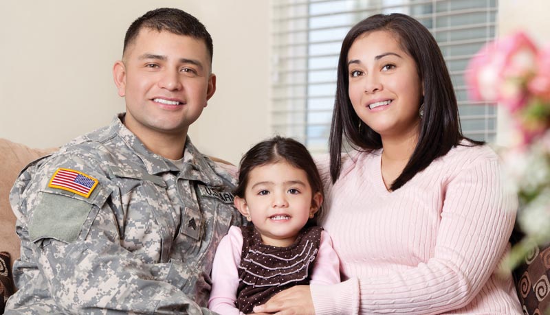 photo of military family smiling on couch in house